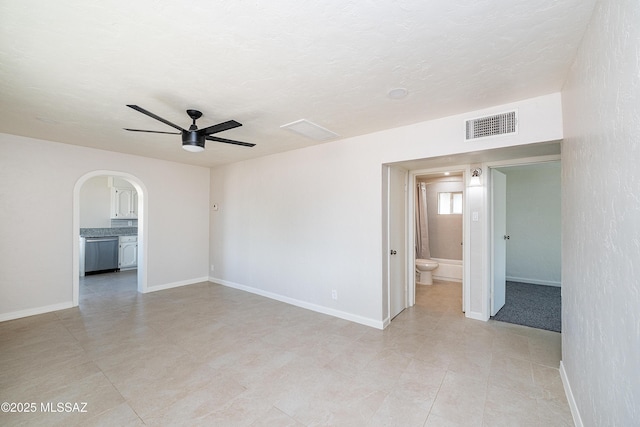 empty room featuring a ceiling fan, arched walkways, baseboards, and light tile patterned flooring