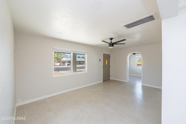 spare room with arched walkways, ceiling fan, and baseboards
