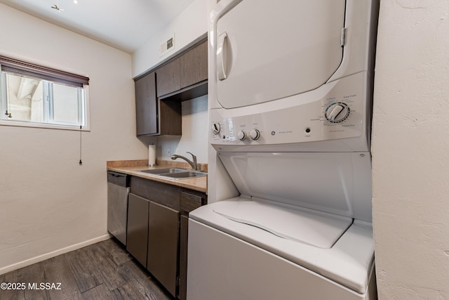 laundry area with estacked washer and dryer, a sink, dark wood-style flooring, and baseboards