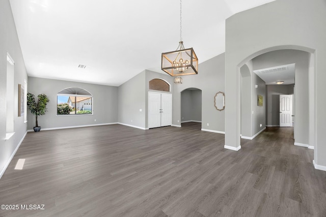 63370 E Whispering Tree Ln, Saddlebrooke, AZ 85739 - unfurnished living room featuring arched walkways, baseboards, dark wood-type flooring, a chandelier, and vaulted ceiling