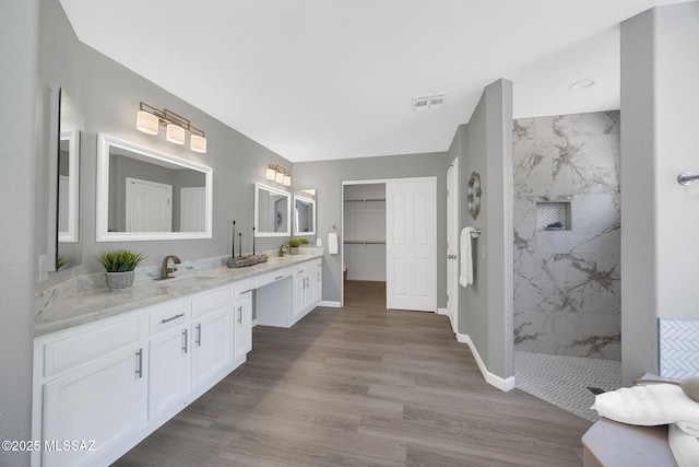 63370 E Whispering Tree Ln, Saddlebrooke, AZ 85739 - bathroom with a marble finish shower, wood finished floors, vanity, baseboards, and a spacious closet