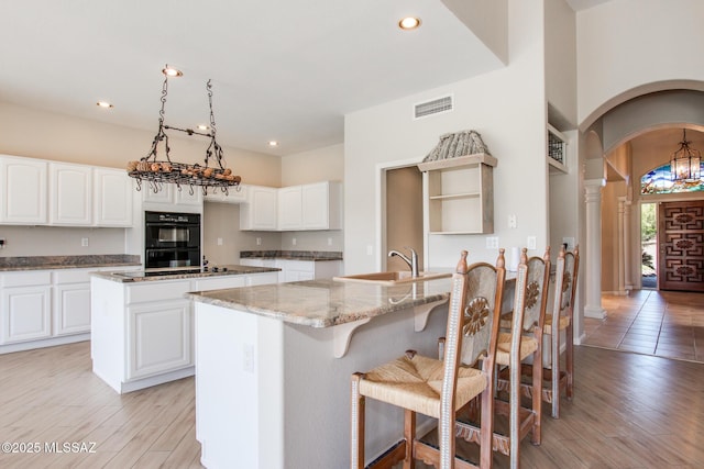 36359 S Wind Crest Dr, Saddlebrooke, AZ 85739 - kitchen featuring a sink, a kitchen island, light stone counters, arched walkways, and recessed lighting