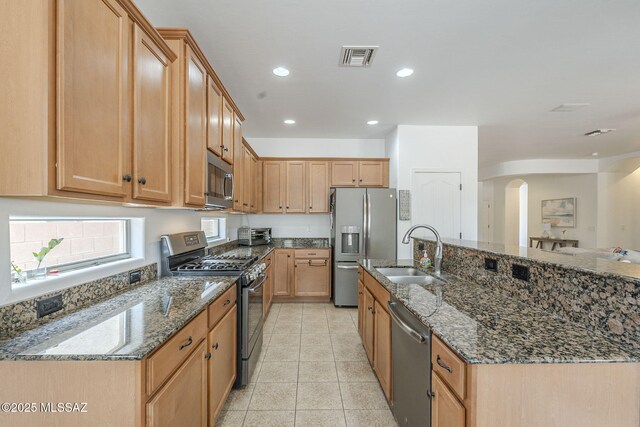 825 E Gunsight Mountain Pl, Sahuarita, AZ 85629 - kitchen with appliances with stainless steel finishes, a sink, arched walkways, light tile patterned flooring, and dark stone counters