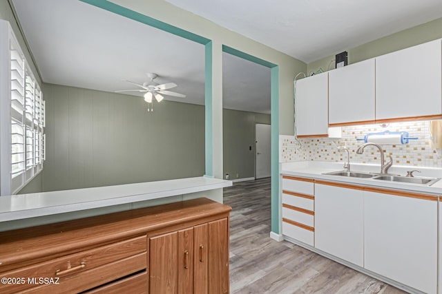 8150 E Broadway Blvd Unit H-107, Tucson, AZ 85710 - kitchen featuring a sink, ceiling fan, light wood-style floors, white cabinets, and backsplash