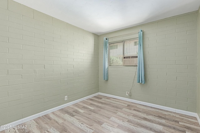 8150 E Broadway Blvd Unit H-107, Tucson, AZ 85710 - spare room featuring baseboards, wood finished floors, brick wall, and cooling unit