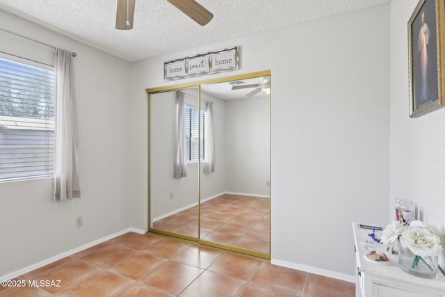 1861 W Sauvignon Dr, Tucson, AZ 85746 - unfurnished bedroom featuring light tile patterned floors, a textured ceiling, a closet, ceiling fan, and baseboards