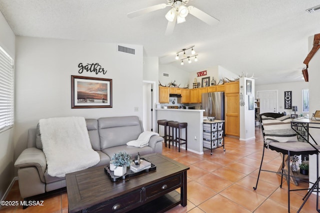 1861 W Sauvignon Dr, Tucson, AZ 85746 - living room featuring ceiling fan, lofted ceiling, a textured ceiling, light tile patterned flooring, and baseboards