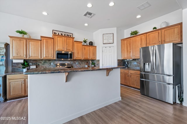 9451 S Via Bandera, Vail, AZ 85641 - kitchen with stainless steel appliances, a center island with sink, light wood-style flooring, tasteful backsplash, and recessed lighting