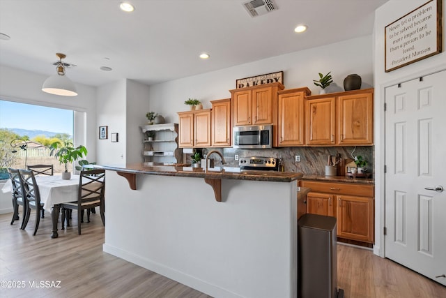 9451 S Via Bandera, Vail, AZ 85641 - kitchen featuring stainless steel appliances, decorative backsplash, a kitchen breakfast bar, a sink, and light wood-style flooring
