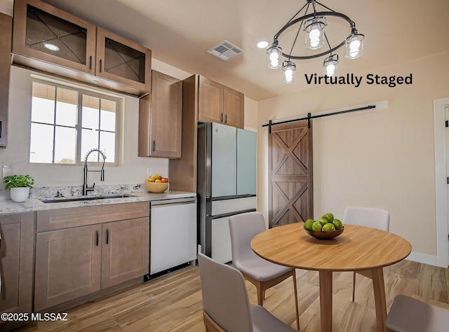 352 W Lee Trl, Safford, AZ 85546 - kitchen featuring stainless steel appliances, a sink, a barn door, light wood finished floors, and light stone counters