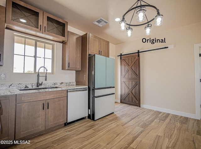 352 W Lee Trl, Safford, AZ 85546 - kitchen with stainless steel appliances, a sink, a barn door, light wood-type flooring, and light stone countertops