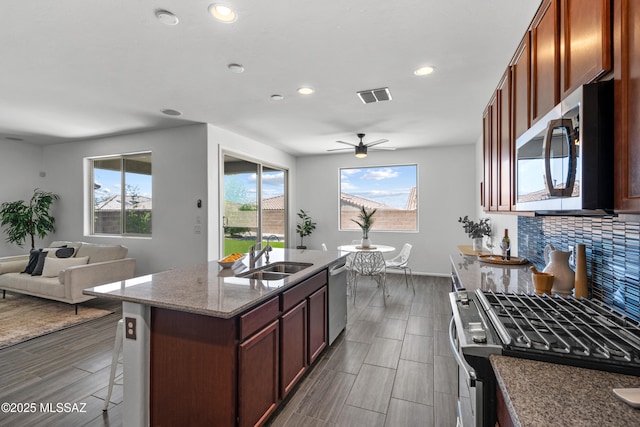 10215 E Bell Rock Trl, Tucson, AZ 85747 - kitchen featuring appliances with stainless steel finishes, a sink, ceiling fan, backsplash, and dark stone counters