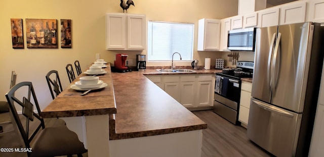 1732 W Pineriver Pl, Tucson, AZ 85746 - kitchen with stainless steel appliances, a sink, a peninsula, white cabinetry, and a breakfast bar