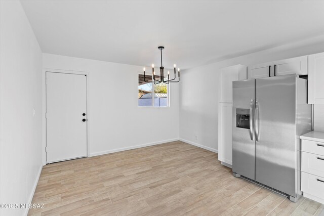 5011 E Scarlett St, Tucson, AZ 85711 - kitchen with stainless steel fridge, a chandelier, light wood-style flooring, white cabinets, and baseboards