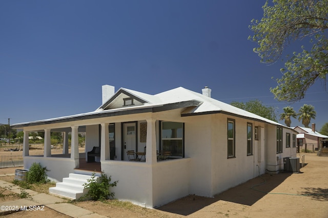 203 N Kellum Ave, Bowie, AZ 85605 - view of front facade featuring a chimney, covered porch, stucco siding, central AC, and fence