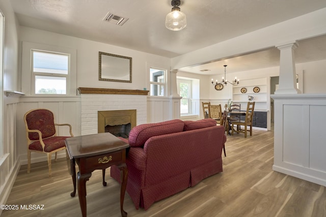203 N Kellum Ave, Bowie, AZ 85605 - living area featuring light wood-style flooring, a fireplace, decorative columns, a decorative wall, and a chandelier