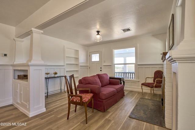 203 N Kellum Ave, Bowie, AZ 85605 - living area with a decorative wall, wood finished floors, built in shelves, wainscoting, and decorative columns