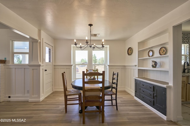 203 N Kellum Ave, Bowie, AZ 85605 - dining area with a decorative wall, a chandelier, wood finished floors, wainscoting, and built in features