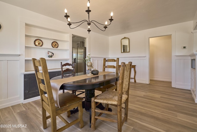 203 N Kellum Ave, Bowie, AZ 85605 - dining area featuring a chandelier, wainscoting, a decorative wall, wood finished floors, and built in shelves