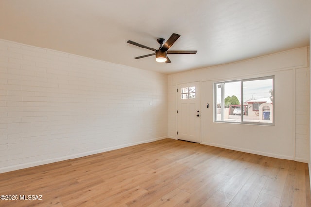 foyer entrance featuring brick wall, a ceiling fan, light wood-style flooring, and baseboards