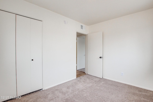 unfurnished bedroom featuring light colored carpet, a closet, and baseboards