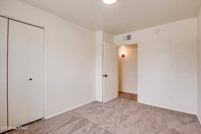 unfurnished bedroom with carpet, a closet, and baseboards
