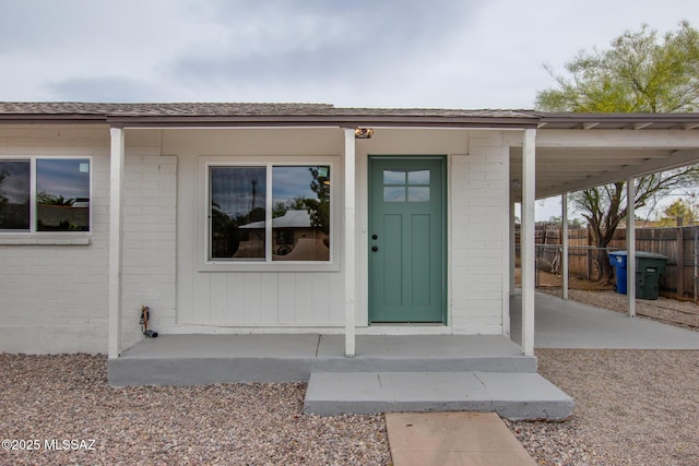 doorway to property featuring fence and brick siding