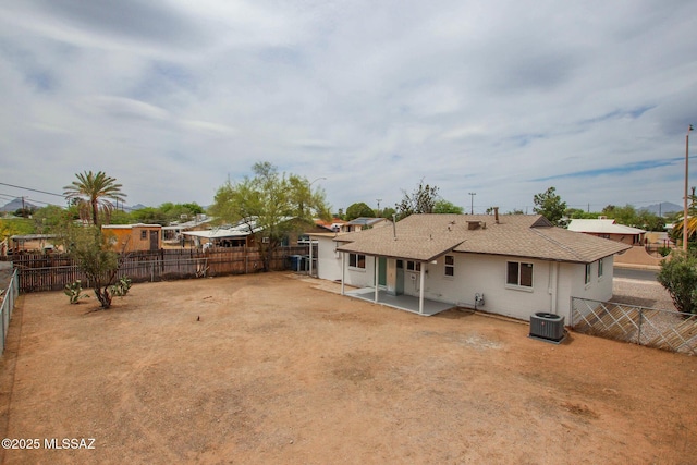 back of house with central AC, a patio, a fenced backyard, roof with shingles, and a residential view