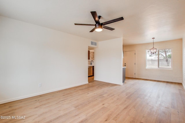 unfurnished room with light wood finished floors, a chandelier, a ceiling fan, and baseboards