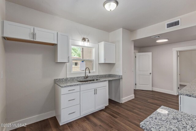 2956 N Tyndall Ave, Tucson, AZ 85719 - kitchen with a sink, baseboards, white cabinetry, light stone countertops, and dark wood-type flooring
