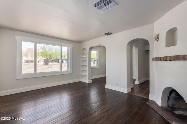 2956 N Tyndall Ave, Tucson, AZ 85719 - unfurnished living room with dark wood-style floors, baseboards, arched walkways, and built in features