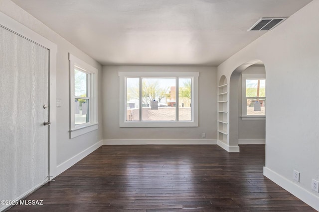 2956 N Tyndall Ave, Tucson, AZ 85719 - spare room featuring dark wood-style floors, baseboards, built in shelves, and arched walkways