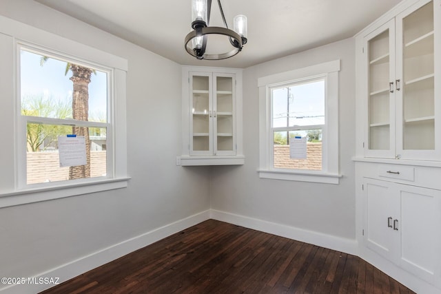 2956 N Tyndall Ave, Tucson, AZ 85719 - unfurnished dining area with a chandelier, baseboards, and dark wood-type flooring