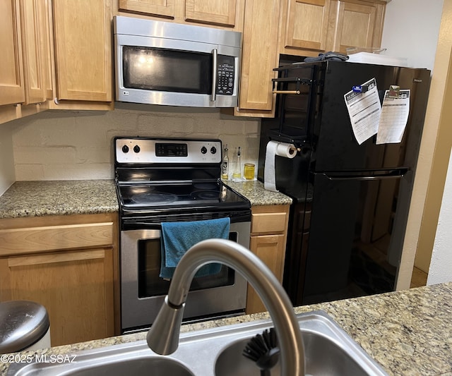 kitchen with appliances with stainless steel finishes, backsplash, and light stone countertops