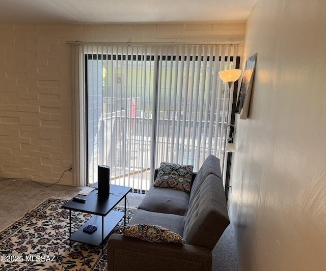 living area featuring carpet and brick wall