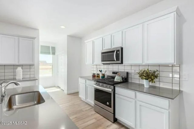 12734 E Russo Dr, Vail, AZ 85641 - kitchen featuring stainless steel appliances, a sink, backsplash, white cabinetry, and light wood-style flooring
