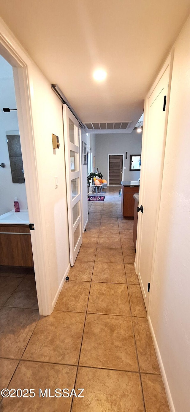 hallway with light tile patterned floors and baseboards