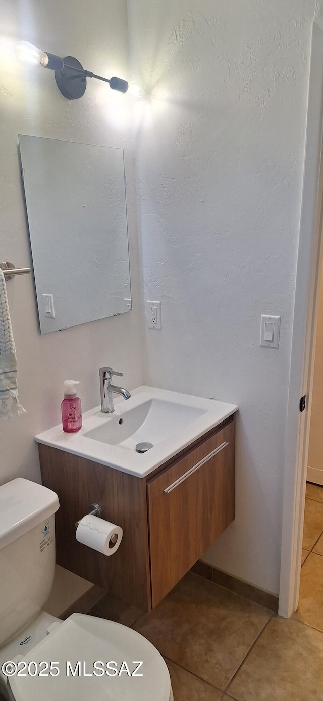 half bath featuring tile patterned flooring, toilet, and vanity