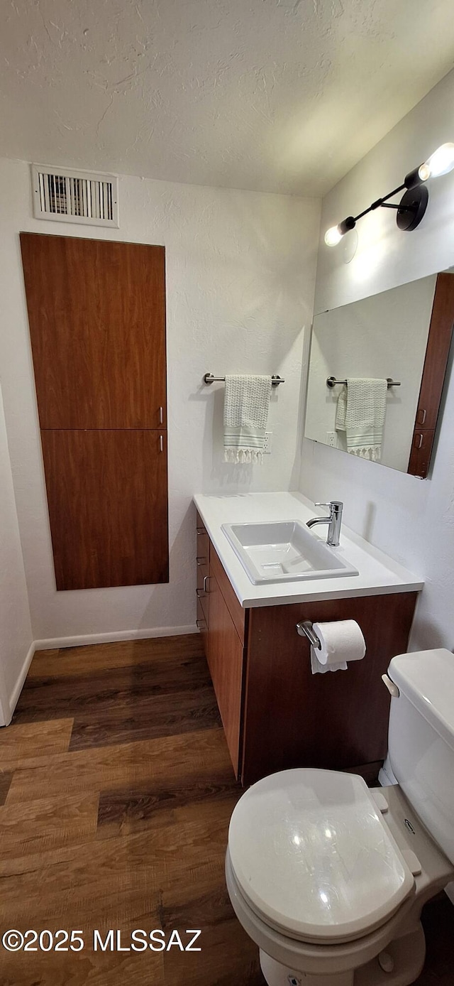 bathroom featuring wood finished floors, toilet, vanity, and a textured ceiling