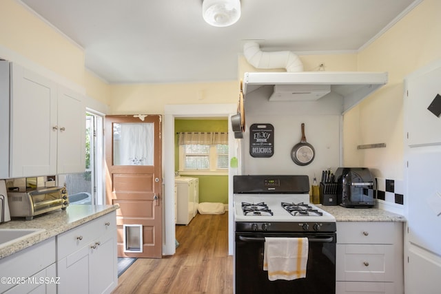 24 Black Knob, Bisbee, AZ 85603 - kitchen with range with gas cooktop, washer and dryer, light wood finished floors, white cabinets, and ornamental molding