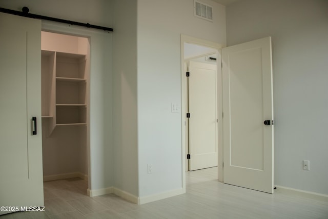 481 Calle Cipres, Rio Rico, AZ 85648 - unfurnished bedroom with a walk in closet, baseboards, and a barn door