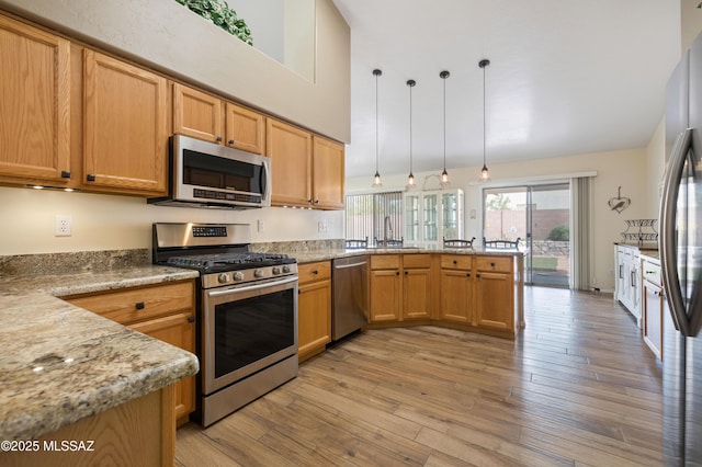 9429 N Elan Ln, Tucson, AZ 85742 - kitchen with stainless steel appliances, a peninsula, light wood-style floors, a sink, and hanging light fixtures