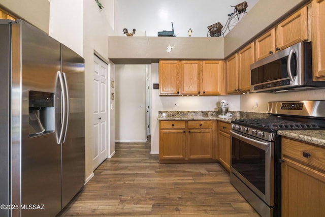 9429 N Elan Ln, Tucson, AZ 85742 - kitchen featuring stainless steel appliances, dark wood finished floors, dark stone countertops, brown cabinets, and a towering ceiling