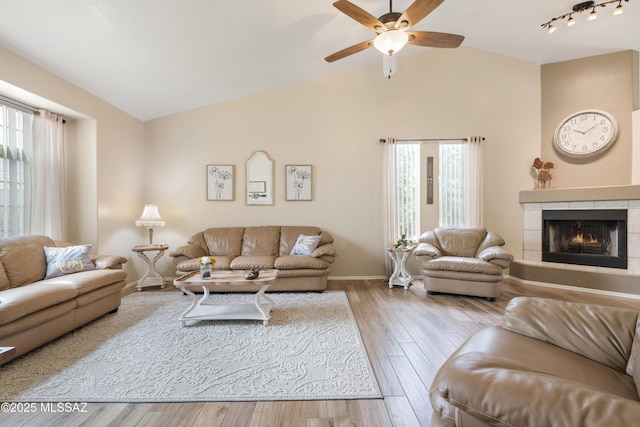 9429 N Elan Ln, Tucson, AZ 85742 - living room featuring a tiled fireplace, ceiling fan, wood finished floors, baseboards, and high vaulted ceiling