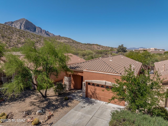 11113 N Rams Horn Trl N, Oro Valley, AZ 85737 - view of front facade featuring an attached garage, concrete driveway, a tile roof, stucco siding, and a mountain view