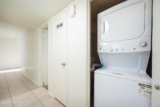 3025 E Blacklidge Dr, Tucson, AZ 85716 - laundry room featuring stacked washer and clothes dryer, light tile patterned floors, and baseboards