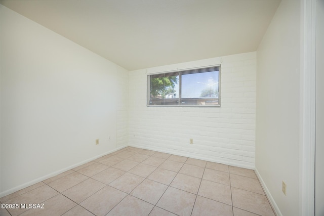 3025 E Blacklidge Dr, Tucson, AZ 85716 - unfurnished room featuring brick wall, light tile patterned flooring, and baseboards