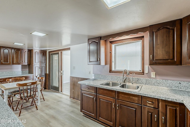 6158 E Calle Aurora, Tucson, AZ 85711 - kitchen with a sink, light countertops, light wood-style floors, and dark brown cabinetry