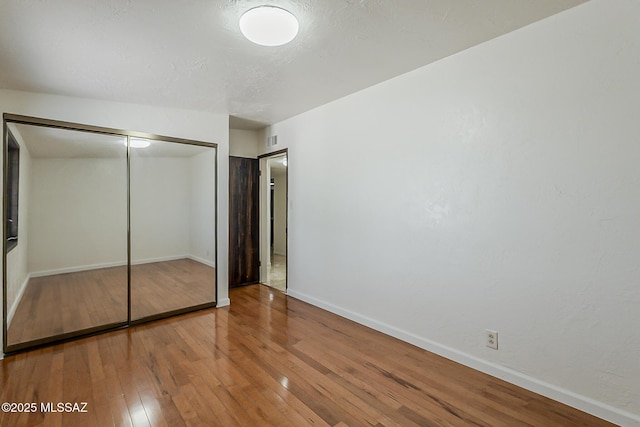 6158 E Calle Aurora, Tucson, AZ 85711 - unfurnished bedroom featuring wood-type flooring, a closet, and baseboards