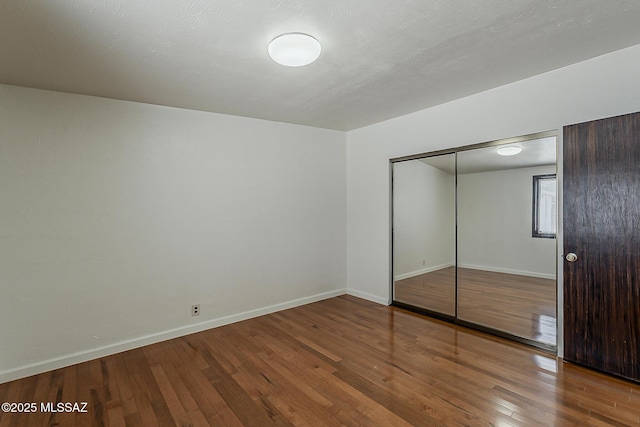 6158 E Calle Aurora, Tucson, AZ 85711 - unfurnished bedroom featuring wood-type flooring, baseboards, and a closet